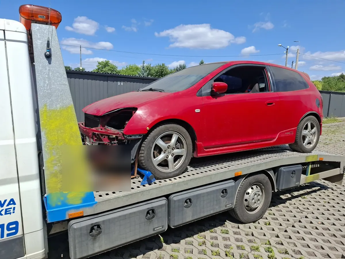 Czerwona Honda Civic z rozbitym przodem na platformie lawety