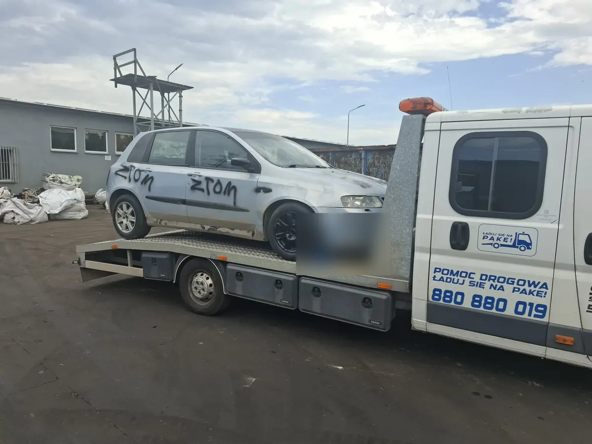 Fiat Stilo na platformie lawety przed budynkiem