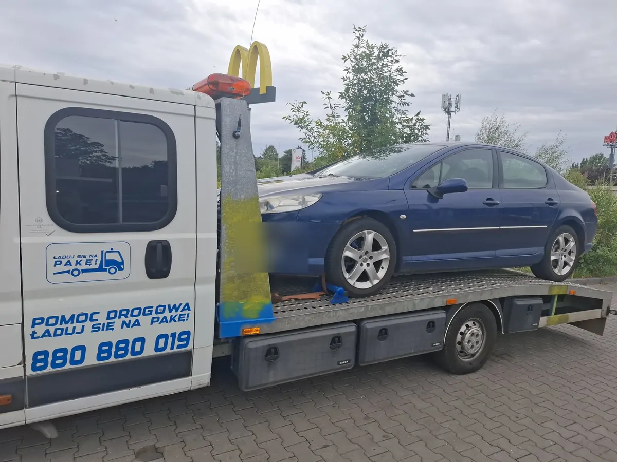 Granatowy Peugeot 407 na platformie lawety